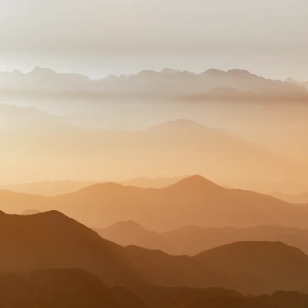 Horizonti beskrajnih planinskih vrhova u toplim tonovima, u portretu.