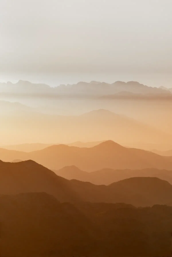 Horizonti beskrajnih planinskih vrhova u toplim tonovima, u portretu.