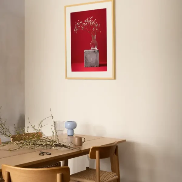 Fotografija sitnog bijelog cvijeća u staklenoj vazi na crvenoj pozadini - slika za zid medium