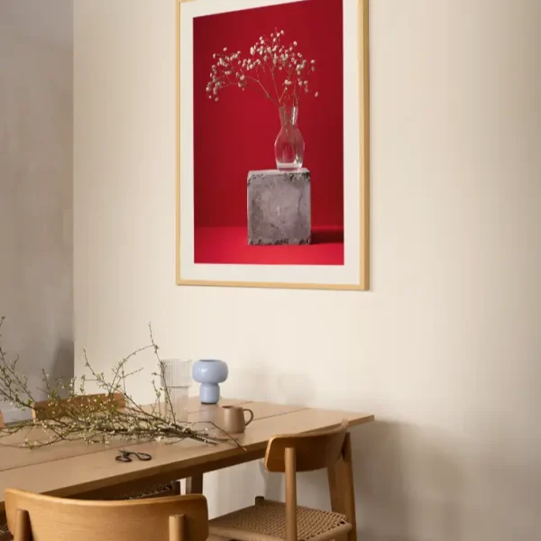 Fotografija sitnog bijelog cvijeća u staklenoj vazi na crvenoj pozadini - slika za zid large